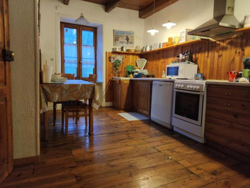 une cuisine avec une cuisinière et une table à l'intérieur dans l'établissement Maison familiale et authentique, à Saint-Jacques-des-Blats