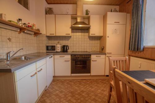 uma cozinha com armários brancos, um lavatório e um frigorífico em Apartment Paletti 23 em Enzingerboden