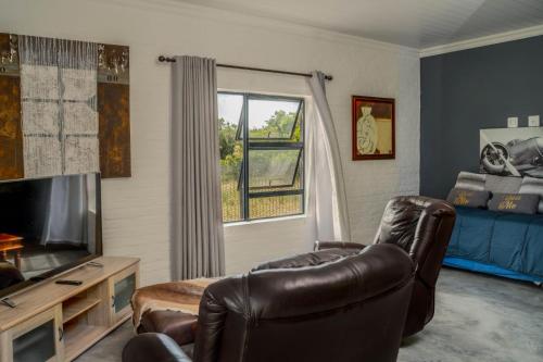 a living room with a leather chair and a television at SkatKus Eco Estate in Stilbaai-Wes