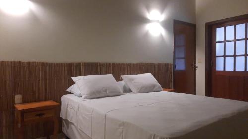 a bedroom with a large white bed with two pillows at Casa Pequizeiro in Pirenópolis
