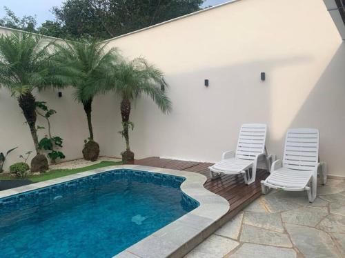 a swimming pool with two chairs next to a house at Casa Pequizeiro in Pirenópolis