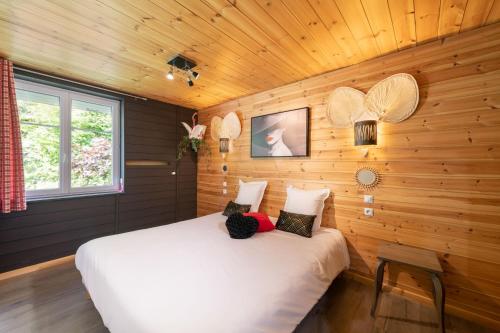 1 dormitorio con 1 cama blanca en una pared de madera en LOGIS Hôtel Restaurant La Vigotte, en Girmont-Val-dʼAjol