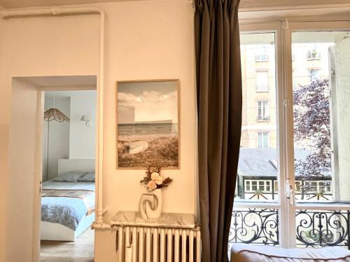 une chambre avec un lit et une grande fenêtre dans l'établissement Dream Dwell Paris-Cozy historic appartement near Exelmans in 16th District Paris, à Paris