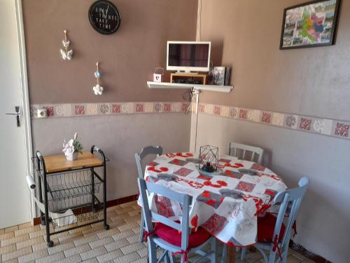 uma sala de jantar com uma mesa com cadeiras e uma televisão em Villa Récompense Côte Atlantique n3 em Soulac-sur-Mer
