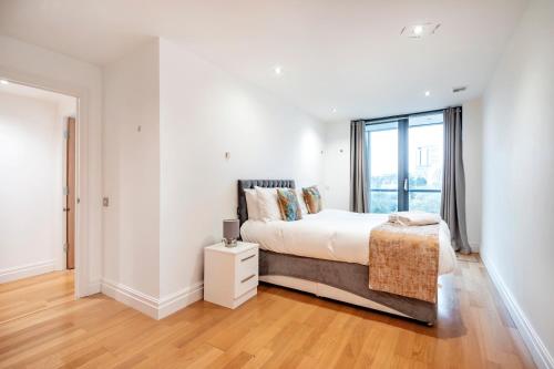 um quarto branco com uma cama e uma janela em Paddington Basin View Apartment em Londres