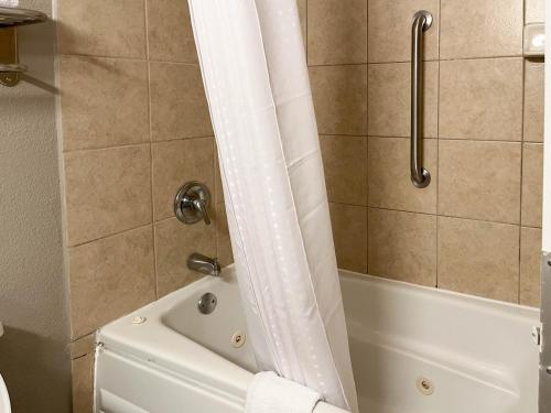 a bathroom with a tub and a shower curtain at Motel 6 Nacogdoches TX SFA University in Nacogdoches