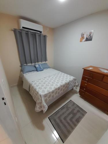 um pequeno quarto com uma cama e uma cómoda em Hospedagem do Elias em Cuiabá