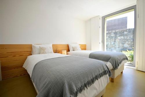 Dos camas en una habitación blanca con ventana. en Villa 292, en Caminha