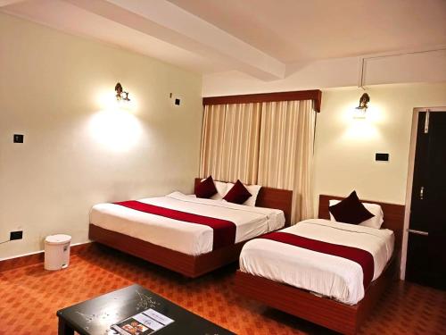 a hotel room with two beds and a table at LILY GUEST HOUSE in Shillong