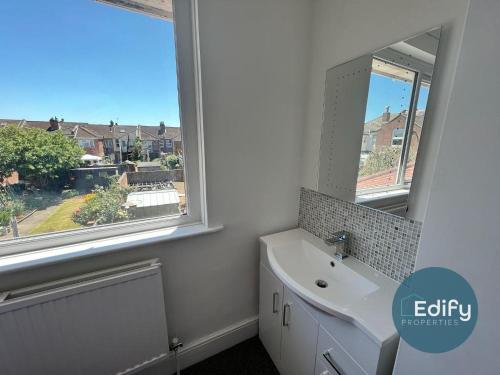 a bathroom with a sink and a mirror and a window at 2 Br Flat Free Parking Great Location in Southampton