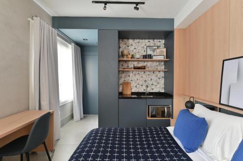 1 dormitorio con cama, escritorio y cocina en Studio Prime, en São Paulo