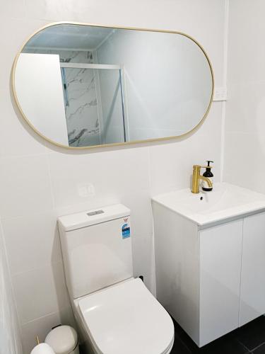 a bathroom with a white toilet and a mirror at Stylish Queen Room 1Min Walk to Station 5Min to City 10Min to Airport in Sydney
