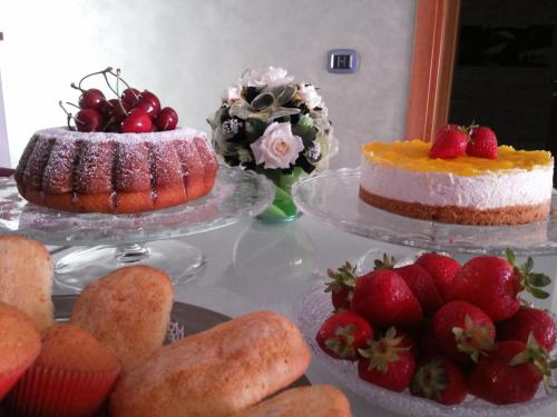 two cakes and strawberries on plates on a table at B&B da Rosario in Campomaggiore