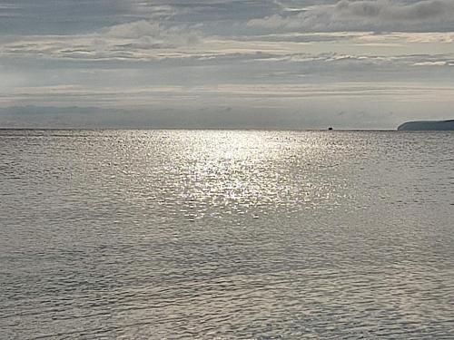 a large body of water with the sun reflecting on it at Wohnung am Wanderweg zum Königsstuhl unter Reet in Lohme