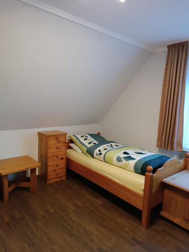 a bedroom with a bed and a dresser and a table at Gästehaus Atrico Schleuse Wg 1 in Surwold