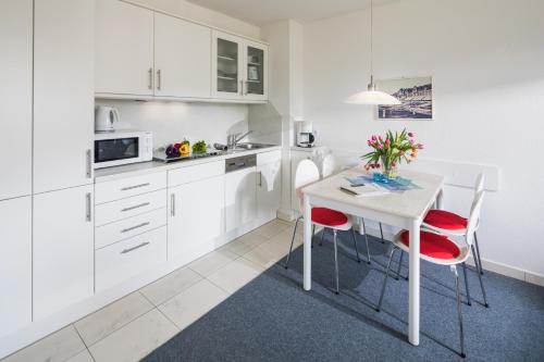 eine Küche mit weißen Schränken und einem Tisch mit roten Stühlen in der Unterkunft Haus Bielefeld Ferienwohnung 29 in Norderney