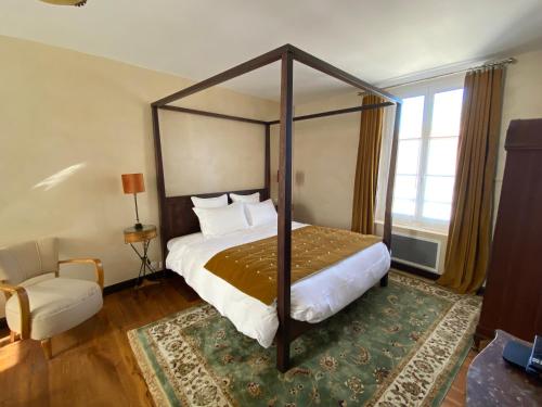 a bedroom with a canopy bed and a chair at LA THEBAUDERIE in Montfort-lʼAmaury