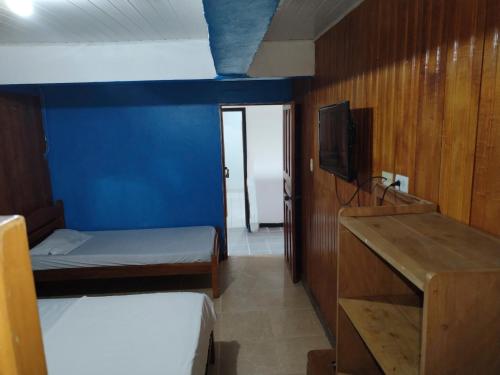 a small room with two beds and a tv at Divino Niño Hotel in Leticia