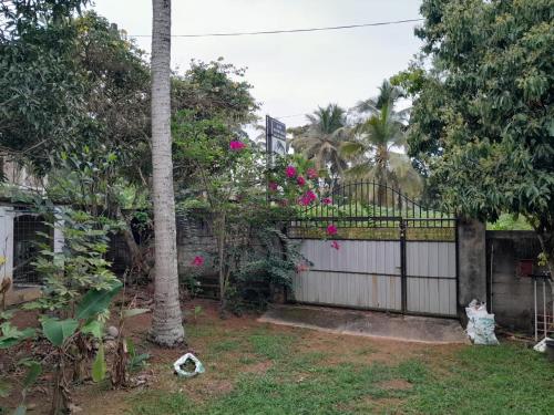 een hek in een tuin met roze bloemen bij Roch home in Ganemulla
