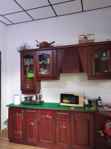 een keuken met houten kasten en een magnetron bij Roch home in Ganemulla