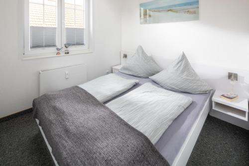 Schlafzimmer mit einem Bett mit weißer Bettwäsche und einem Fenster in der Unterkunft Haus Bielefeld Ferienwohnung 12 in Norderney