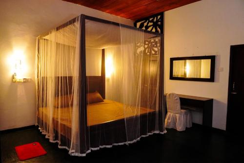 a bedroom with a canopy bed with curtains at Villa Nadya Guesthouse in Pilana