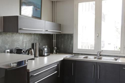 ボルドーにあるGrand Lebrun - Appartement 3 chambres avec ascenseur - Caudéranのキッチン(黒いキャビネット、シンク、窓付)