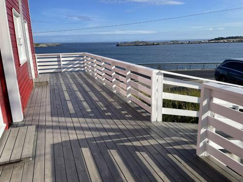a wooden deck with a white fence next to the water at Edith Huset in Moskenes