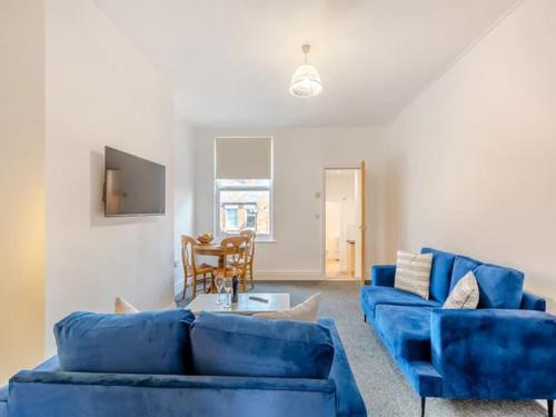 a living room with two blue couches and a table at Charles Alexander Short Stay - Clifton House Apartment in Lytham St Annes