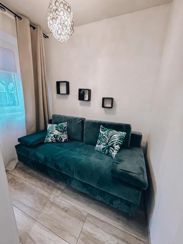 a green couch in a living room with a chandelier at Parkowy Kudowa in Kudowa-Zdrój