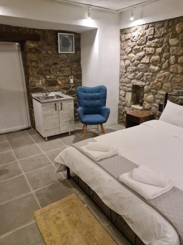 a bedroom with a bed and a blue chair at Villas Kertezi in Kalavrita