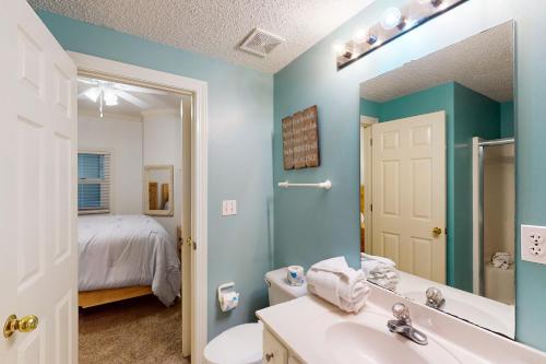 a bathroom with a sink and a mirror and a bed at Enclave 304 in Orange Beach