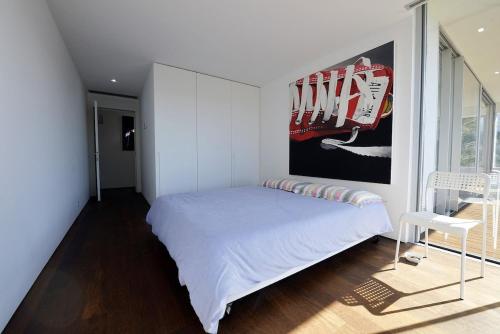 Dormitorio blanco con cama y póster en la pared en Villa 297, en Caminha