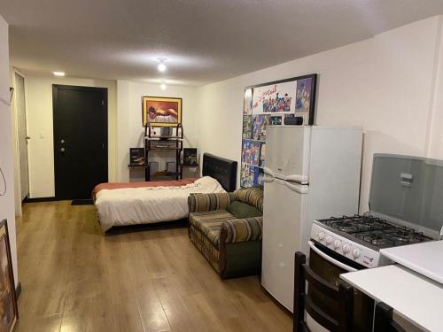 een woonkamer met een bed en een koelkast bij Hermosa Suite para largas estadías con parqueadero in Quito