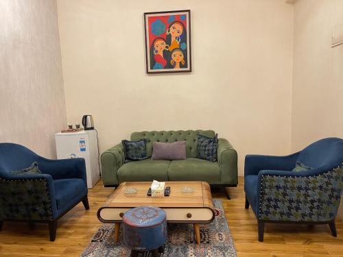 a living room with a green couch and two chairs at Al-Rabie Hotel & Apartments in Baghdād