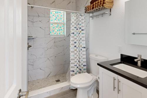 een witte badkamer met een toilet en een douche bij Sea Grape Getaway in Marathon