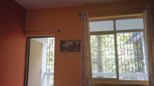 een raam in een kamer met een gordijn en een spiegel bij Yago's Hideout in Bogmalo