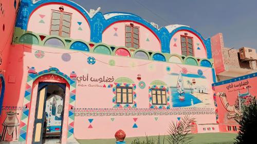 un edificio rosa con un dipinto sopra di Fadlos Anay Nubian Guesthouse فضلوس أناي a Aswan