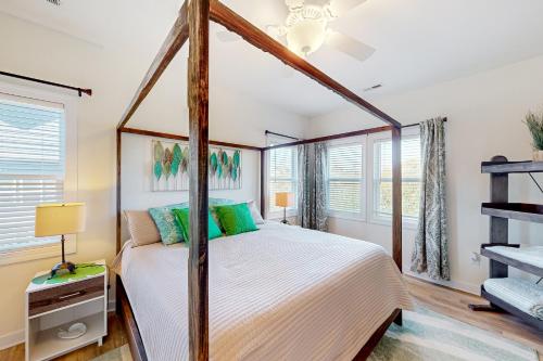 een slaapkamer met een hemelbed en ramen bij Saylor’s Sandcastle in Surf City