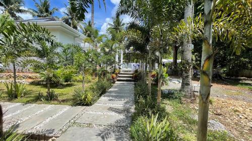 a garden with palm trees and a walkway at LA PARISIENNE PRIVÂTE BOTANICAL GARDEN RESORT 