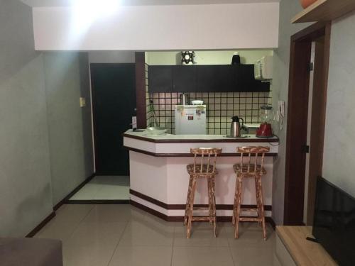 a kitchen with two stools at a kitchen counter at Amplo Quarto e sala decorado in Salvador