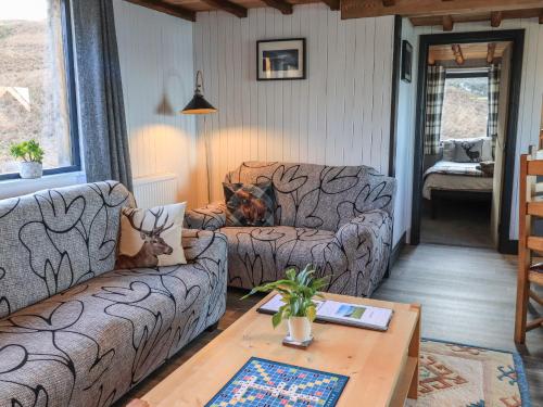 a living room with two couches and a table at Doune Bay Lodge in Mallaig