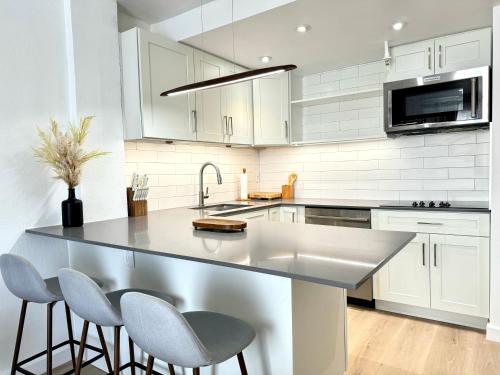 a kitchen with white cabinets and a large island with stools at High-End Apartment, Across the Beach in Miami Beach