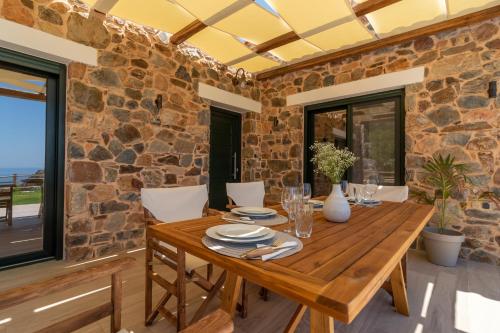 a dining room with a wooden table and a stone wall at Aoria Villas in Palaiochóra