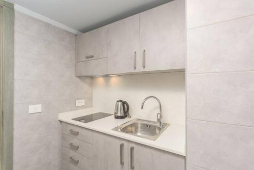 uma pequena cozinha com um lavatório e armários brancos em Vibe 205, Modern 2 Bedroom Apartment in Awkar em Dbayeh