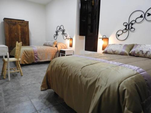 a bedroom with two beds and a table and a chair at Mesón del Alcalde in Lagos de Moreno
