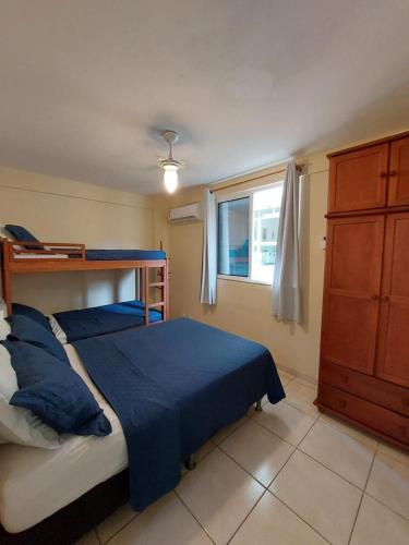 1 dormitorio con cama con sábanas azules y ventana en Aconchego da Prainha dois quartos, ar condicionado, wifi , duas vagas de garagem, en Arraial do Cabo