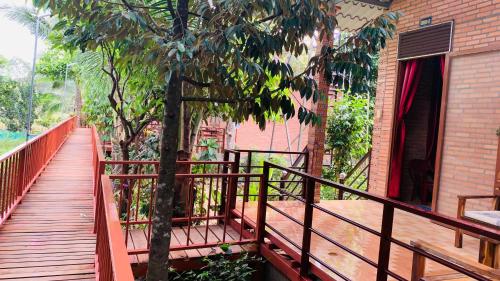 a wooden walkway next to a building with a tree at Gibbon Singing Home Stay in Quan Tom