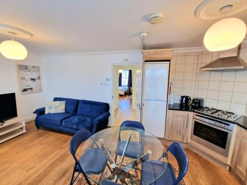 uma sala de estar com uma mesa de vidro e um sofá azul em Cosy Home in Kensington - 2 minutes to Subway/Tube - Ealrs Court Station em Londres
