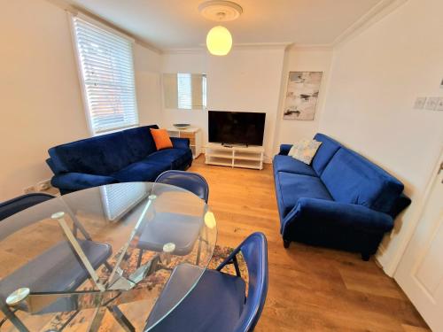 uma sala de estar com sofás azuis e uma televisão em Cosy Home in Kensington - 2 minutes to Subway/Tube - Ealrs Court Station em Londres